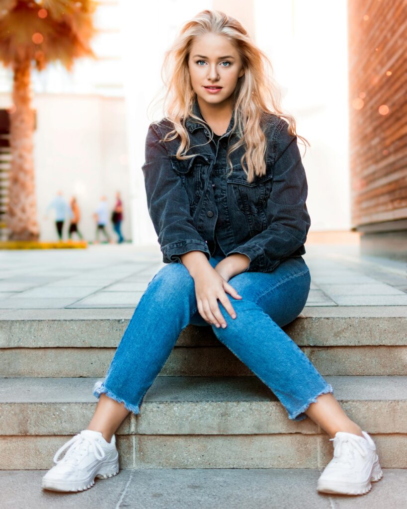 Woman sitting on steps, wearing casual outfit.